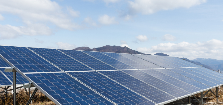 Solar panels on a field with mountains in the background